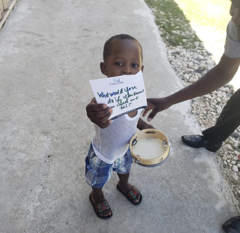 A child holding a Calling dream card and a tambourine